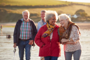Group,Of,Smiling,Senior,Friends,Walking,Arm,In,Arm,Along